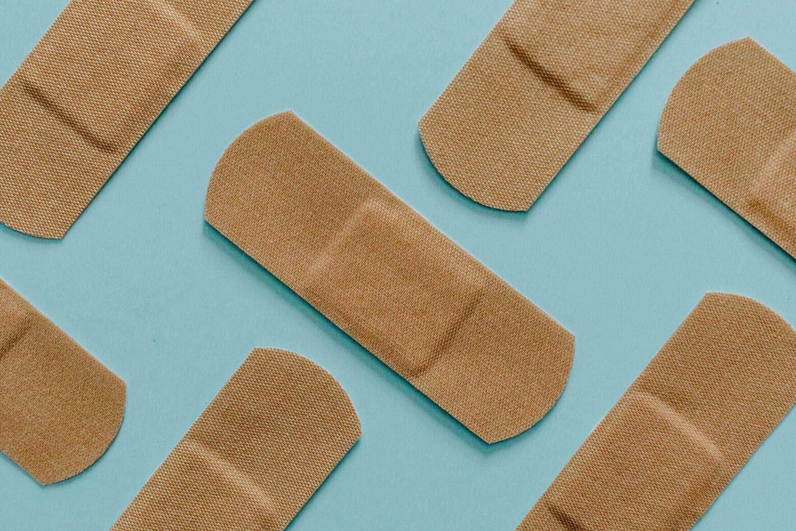 Various sizes of adhesive bandages on blue background.